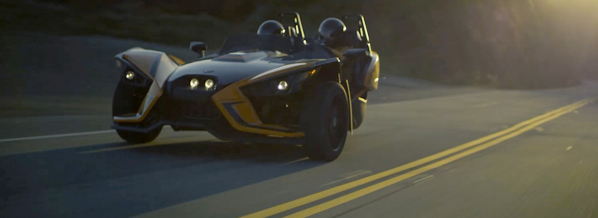 Two seat roadster driving down curvy road at dusk