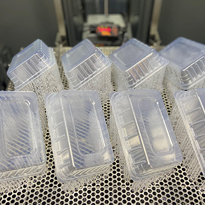 Transparent SLA 3D printed trays arranged on a perforated metal build platform