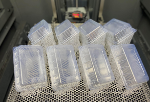 Transparent SLA 3D printed trays arranged on a perforated metal build platform