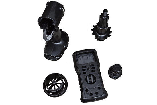 Black 3D printed functional prototypes including gears, housing components, and a turbine-like part