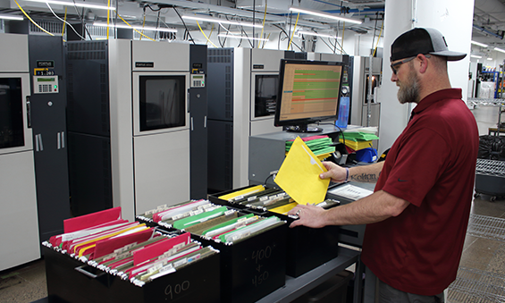 Man sorting folders and keeping track of orders to show traceability at work at Stratasys Direct