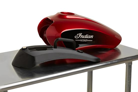 Red Indian Scout motorcycle gas tank next to a black 3D-printed prototype of an alignment jig used for precision assembly.